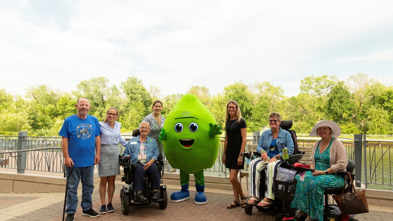 a group of people pose with a green mascot outside